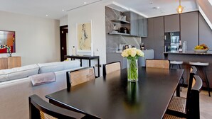 Un espace repas moderne avec une table en bois foncé, des sièges blancs rembourrés et un vase rempli de fleurs.