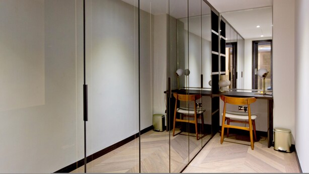 Une pièce moderne avec une cloison en verre, un bureau, deux chaises et une lampe.
