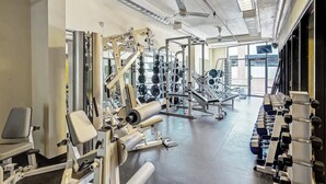 Ein Fitnessstudio mit verschiedenen Trainingsgeräten, Gewitterregalen und einem Deckenventilator.