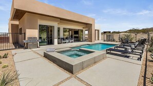 A modern house with a swimming pool, outdoor seating, and a barbecue area.