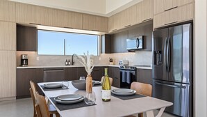 A modern kitchen with a dining area, stainless steel appliances, and a large window.