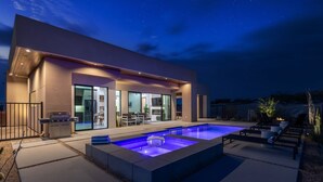 A modern house with a swimming pool, outdoor seating, and a barbecue area.