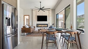 Una cocina moderna con refrigerador empotrado, una zona de comedor con una mesa y sillas grandes, una chimenea y un ventanal con vistas al exterior.