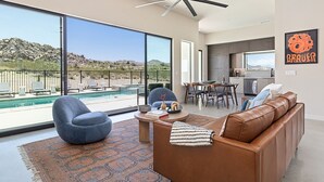 Una sala de estar moderna con piscina, sofá de cuero y comedor.