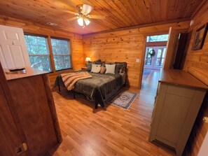 A wooden cabin bedroom with a bed, bedside table, and a ceiling fan.
