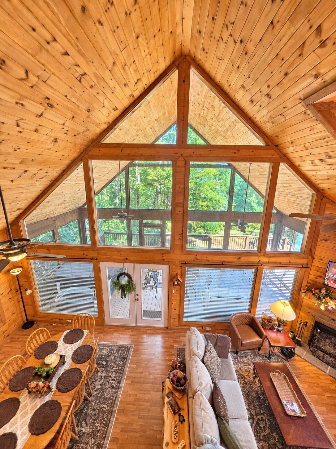 A spacious loft with a high ceiling, large windows, a dining area, a sofa, and a fireplace.