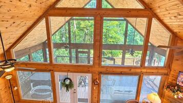 A spacious loft with a high ceiling, large windows, a dining area, a sofa, and a fireplace.