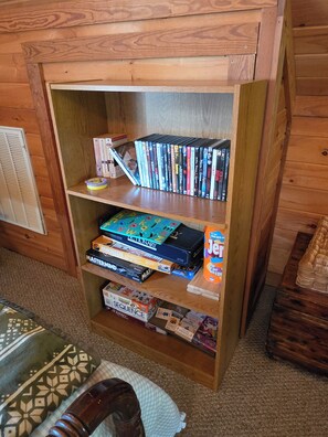 Une bibliothèque en bois contenant divers jeux de société et DVD.