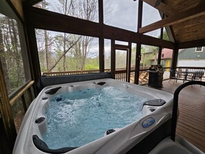 A hot tub with a view of a deck and outdoor furniture.