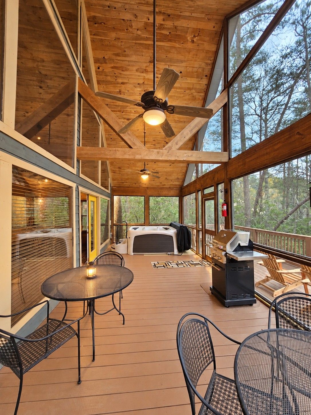 A covered outdoor deck with a ceiling fan, a grill, and seating.