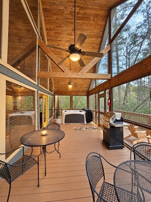 A covered outdoor deck with a ceiling fan, a grill, and seating.