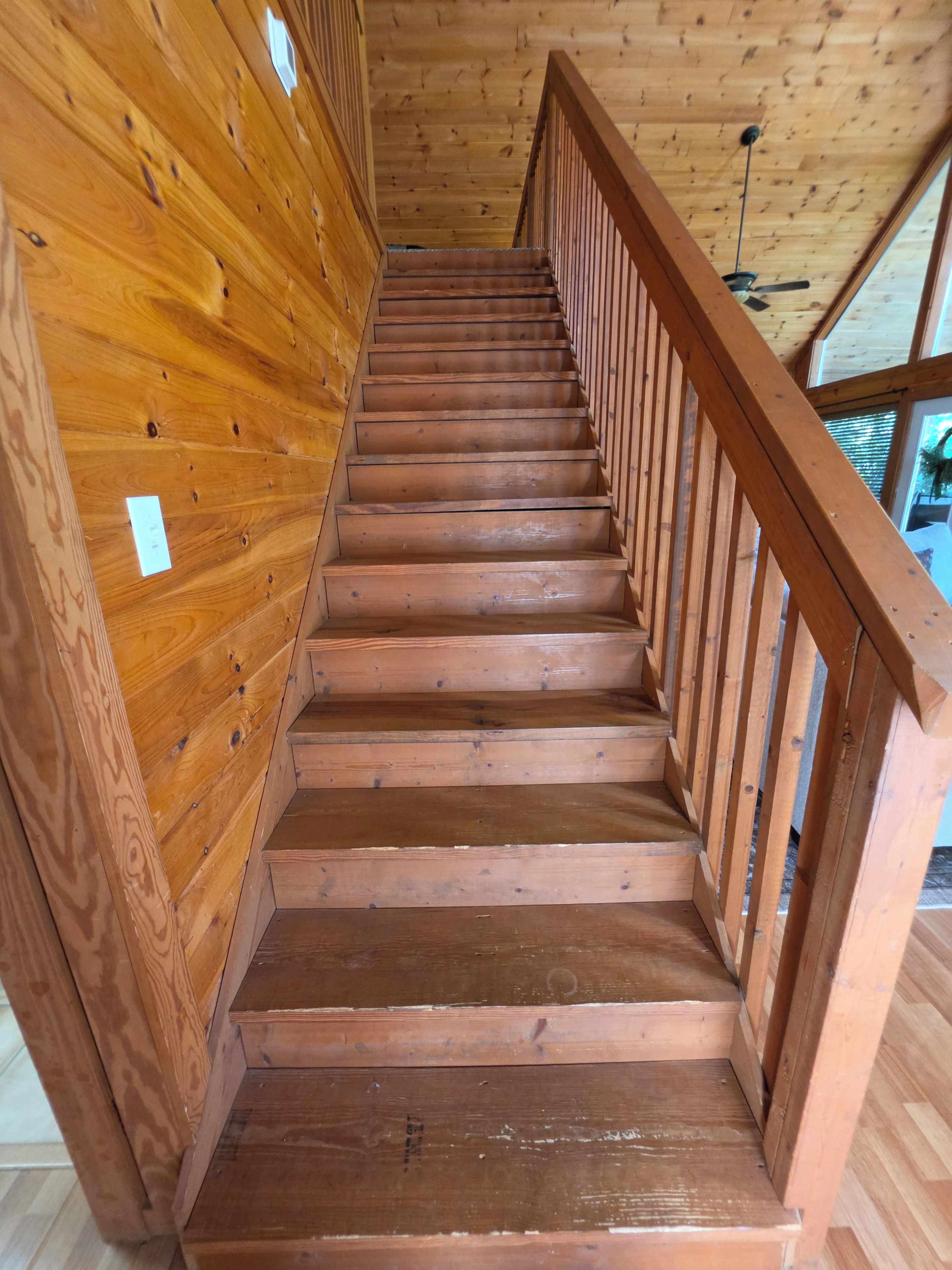 Un escalier en bois avec une rampe, menant à l’étage supérieur.