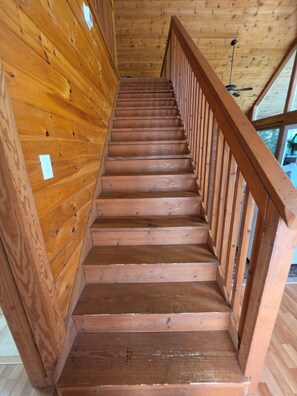 A wooden staircase with a railing, leading to an upper floor.
