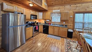 Cucina in legno con frigorifero in acciaio inossidabile, microonde, fornello e lavandino.
