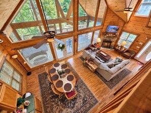 Un intérieur spacieux en bois, avec un plafond haut, de grandes fenêtres, une cheminée et un coin repas.