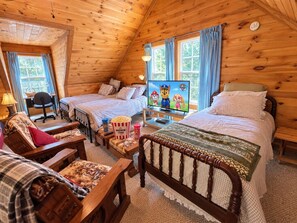 Une chambre confortable, aménagée dans le style d’un chalet, avec deux lits, une télévision et un bureau avec une chaise.