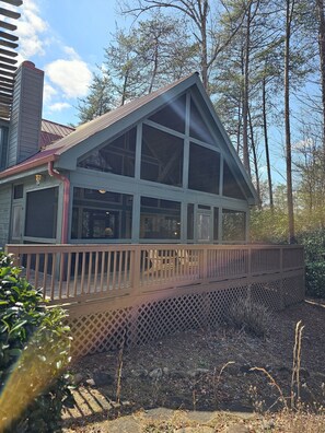 A house with a large deck, a covered porch, and a chimney.