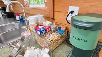 Una cuina sencera amb una cafetera, un cistell de pa i un recipient de cartró amb llet.