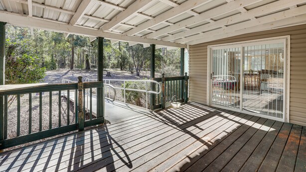 A covered outdoor area with a wooden deck, a glass door leading to a patio, and a view of a forested area. - Work, Play & Explore! Retreat w/ Deck in McAlpin (McAlpin)