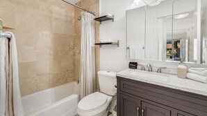 Un baño con bañera, inodoro y un espejo grande.