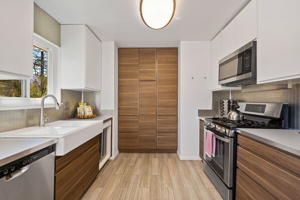Una cocina moderna con armarios blancos, una estufa de acero inoxidable y una pared de acento de madera.