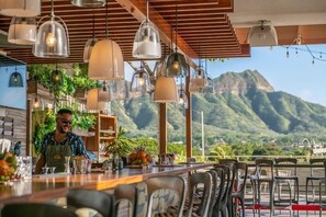 Ein Restaurant mit Barbereich, Stühlen und Bergblick.