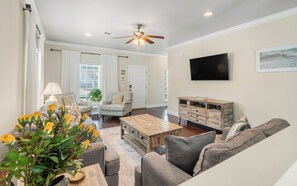 A living room with a sofa set, a coffee table, a television, and a ceiling fan.