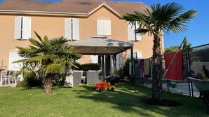 A house with a covered patio, a lawn, and a palm tree.