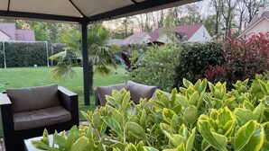 A covered patio area with outdoor furniture and lush greenery.
