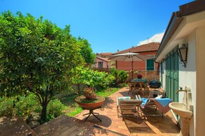 A patio area with a table and chairs, a large potted plant, and a hanging chair.