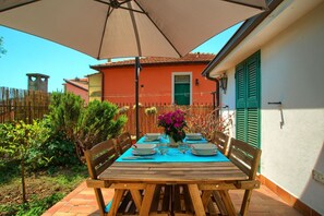 A wooden table set for four with a blue tablecloth, surrounded by chairs, under a large umbrella. - House near downtown with garden box and wi-fi (IMPERIA)