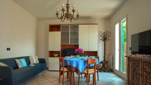 A dining area with a table set for four, a blue tablecloth, and a chandelier above.