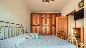 A bedroom with a bed, wooden wardrobe, and a television.