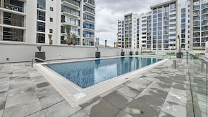 Una piscina en la azotea con vistas a edificios de apartamentos modernos.