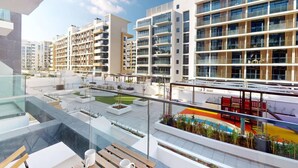 Un edificio residencial moderno con varios balcones, un jardín en la azotea y un mural colorido en la fachada.