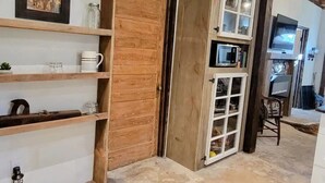 Un interior rústico con estantes de madera, una puerta de madera y un mueble con puertas de cristal.