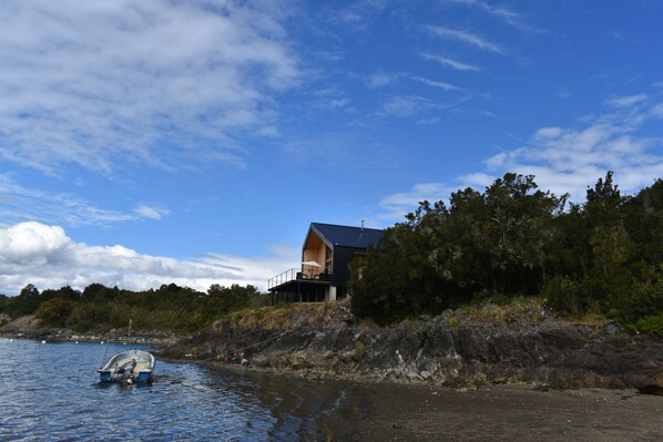 A modern house by a lake with a boat in the water.