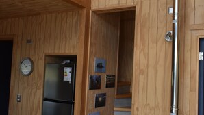 Eine Küche mit Holzwandverkleidung, einem schwarzen Kühlschrank, einem Herd und einer Uhr an der Wand.