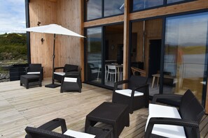 A wooden deck with outdoor furniture, including chairs and tables, and a large umbrella.