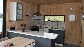 Eine moderne Küche mit Holzwänden, einer großen Kochinsel und einem Fenster mit Blick auf Grünflächen.