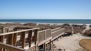 Una passerella di legno che conduce a una spiaggia sotto un cielo sereno.