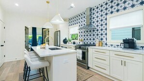 Una cucina moderna con isola centrale, elettrodomestici in acciaio inossidabile e una parete attrezzata con motivi a stella.