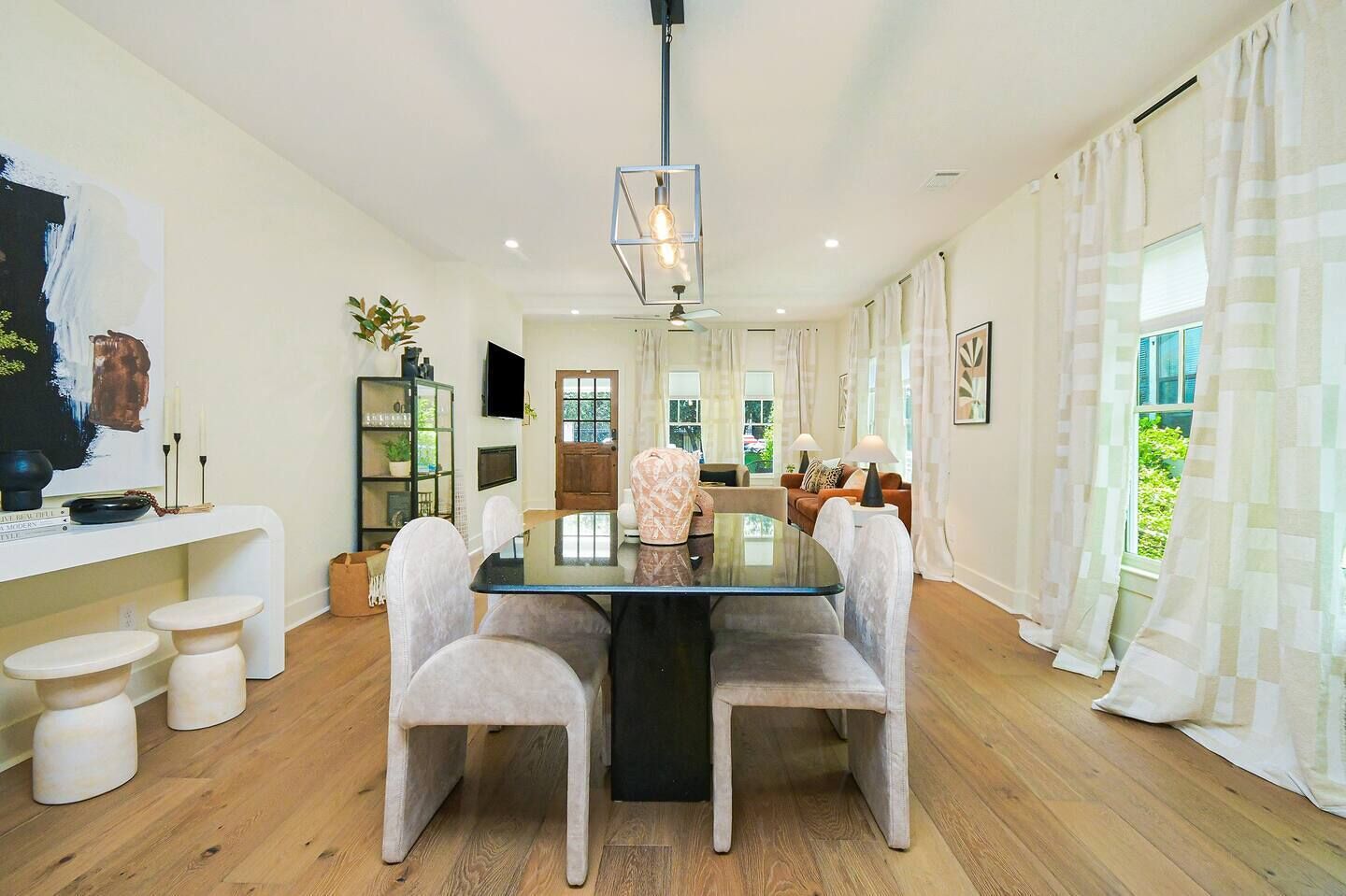 Een ruime eethoek met een glazen tafel, witte stoelen en een moderne hanglamp.