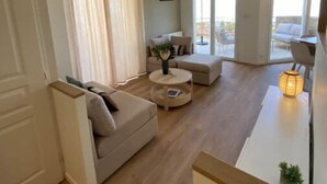 Ein großzügiger Wohnbereich mit einer Couch, einem Couchtisch und einer Pendelleuchte.