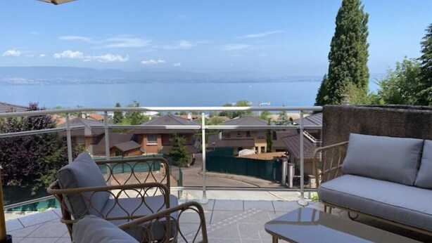 Ein Balkon mit Meerblick, Korbmöbeln und einem Pool im Hintergrund.