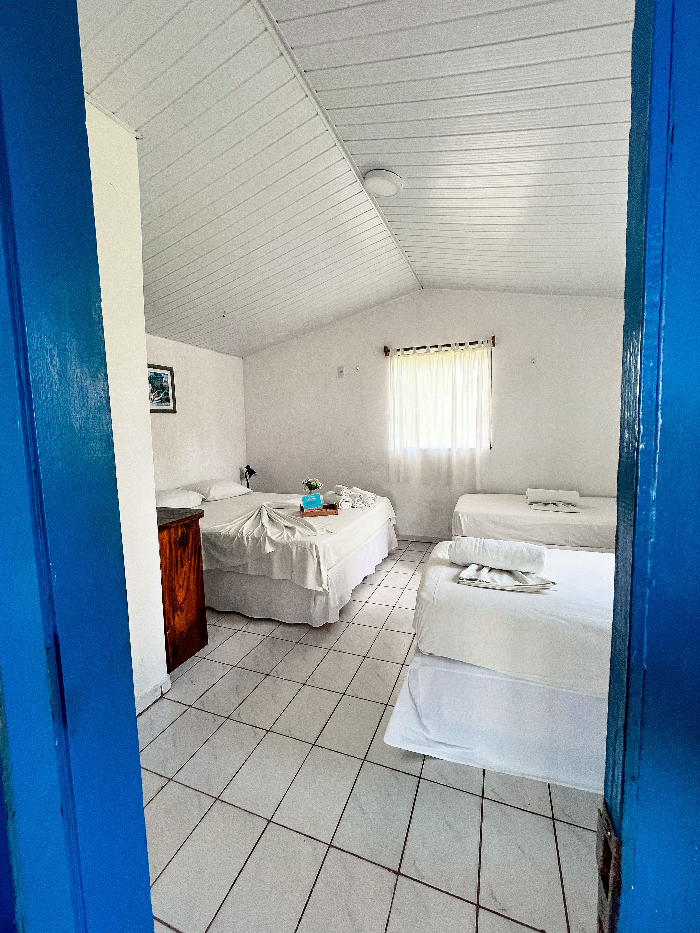 A hotel room with two beds, a small table, and a window with curtains.