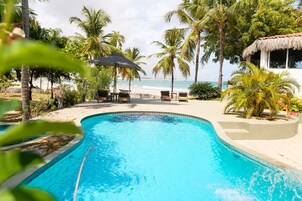 Una piscina al aire libre, sombrillas, sillones reclinables de piscina