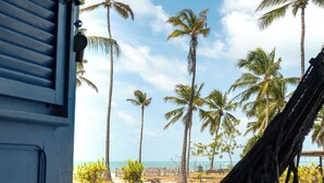 A hammock view overlooking palm trees and a beach. - Pousada Les Alizes (Amontada)