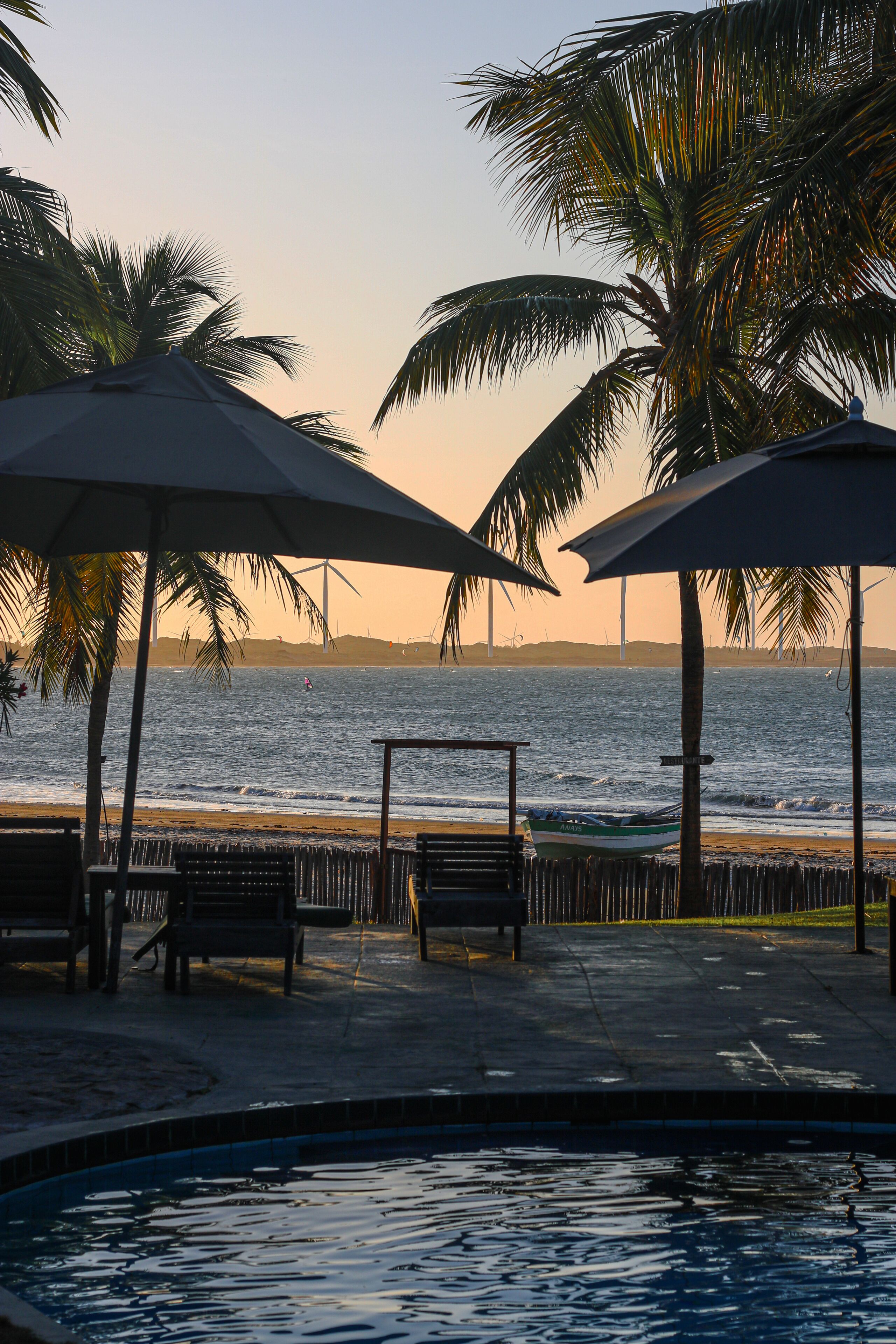 A poolside area with umbrellas, benches, and a view of the ocean.