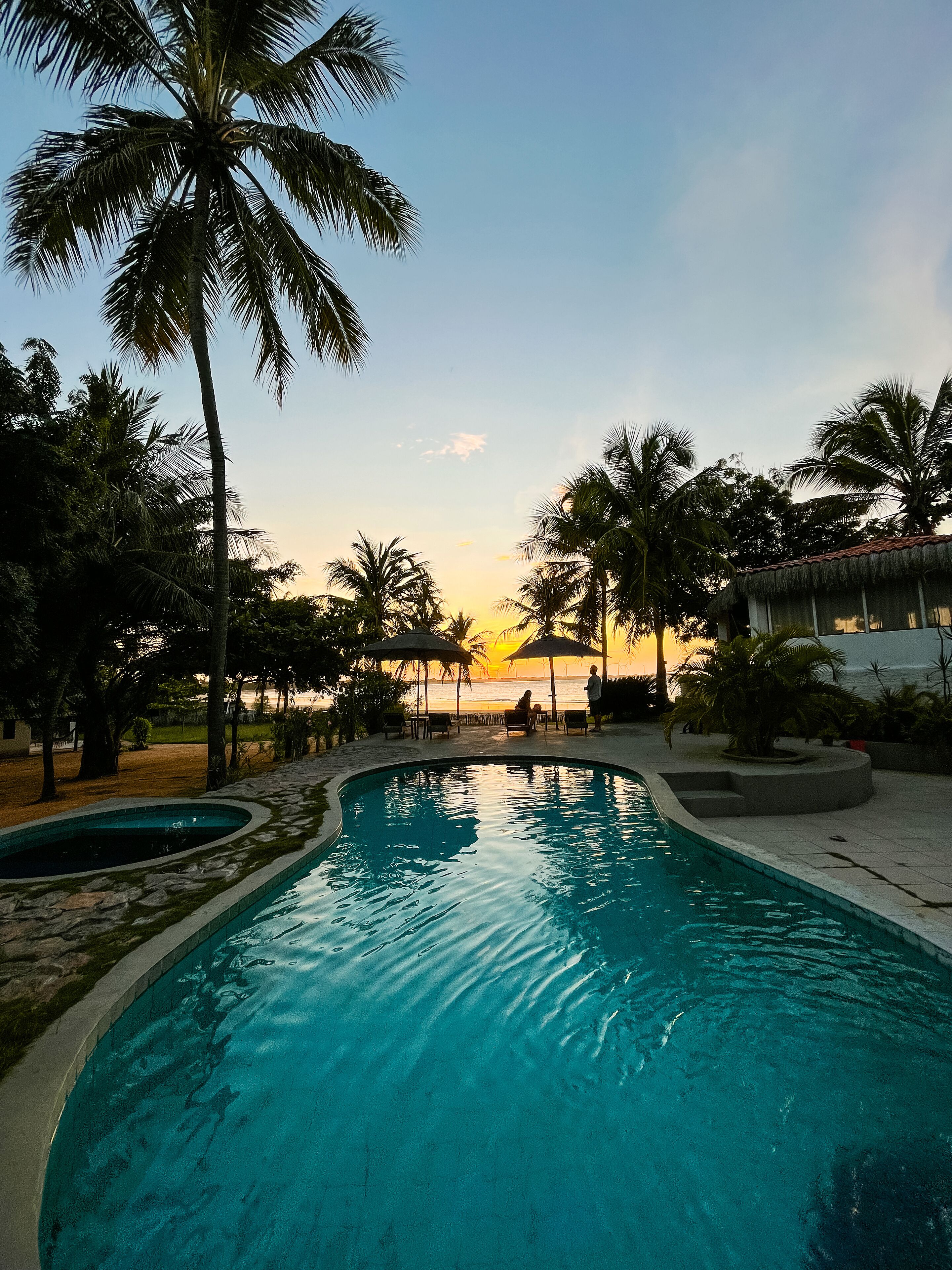 Une piscine bordée de palmiers, avec une vue imprenable sur le coucher de soleil.